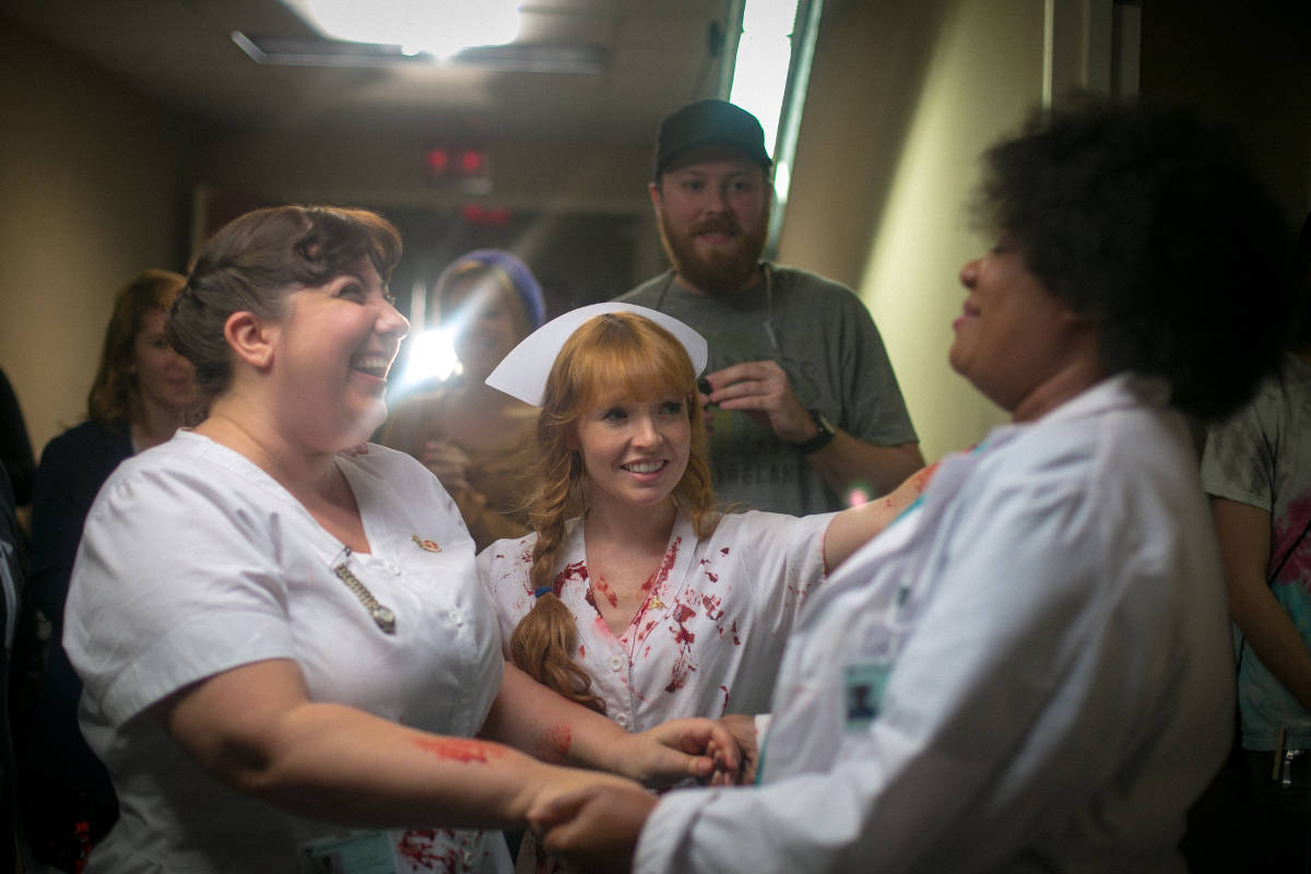 The whole crew looks on as Ashlie Atkinson, and Stef Dawson celebrate a wrap picture on Adrienne C. Moore.